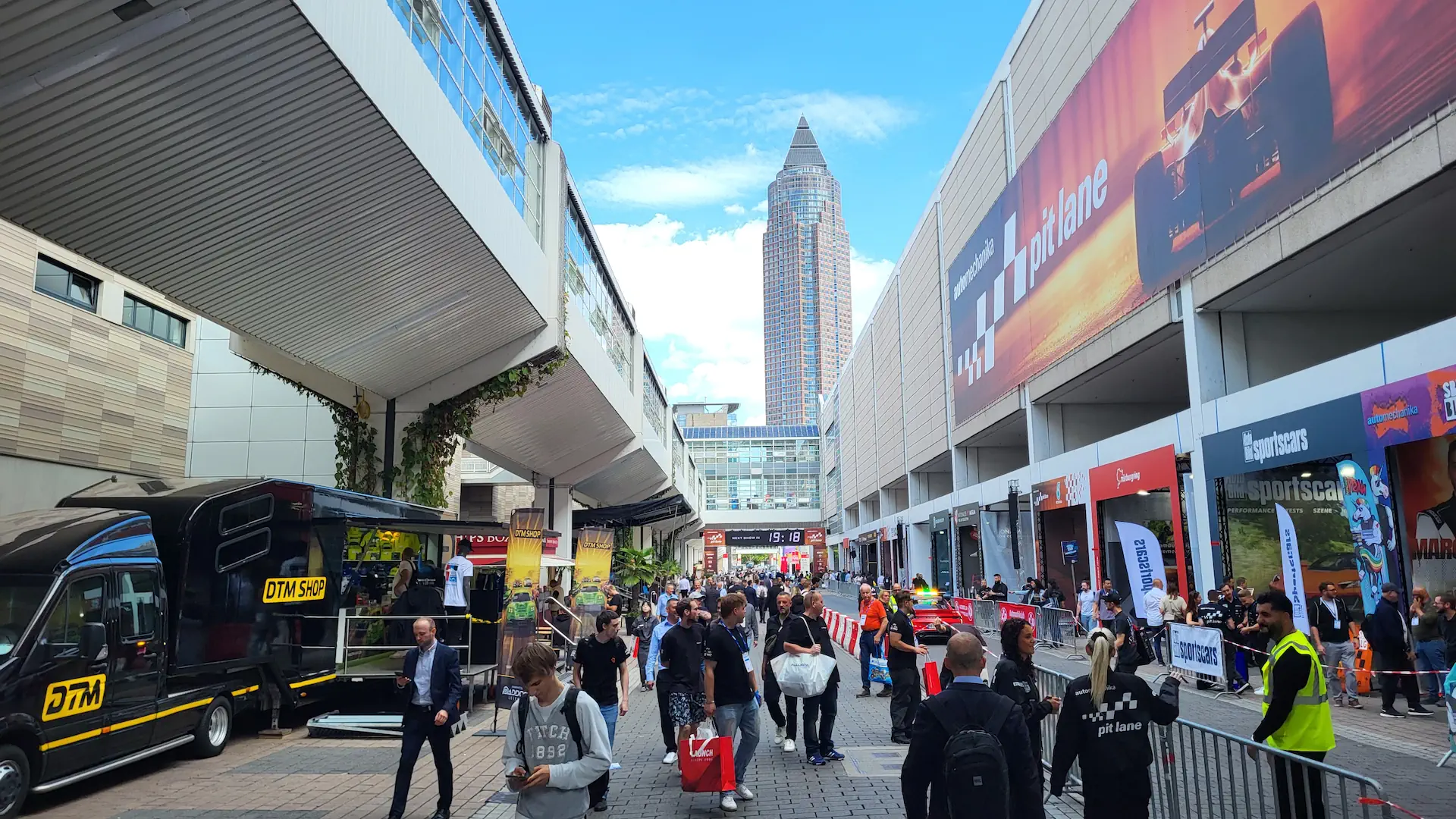 Automechanika 2026: Pit-Lane Boxengasse mit Messeturm und Besuchern